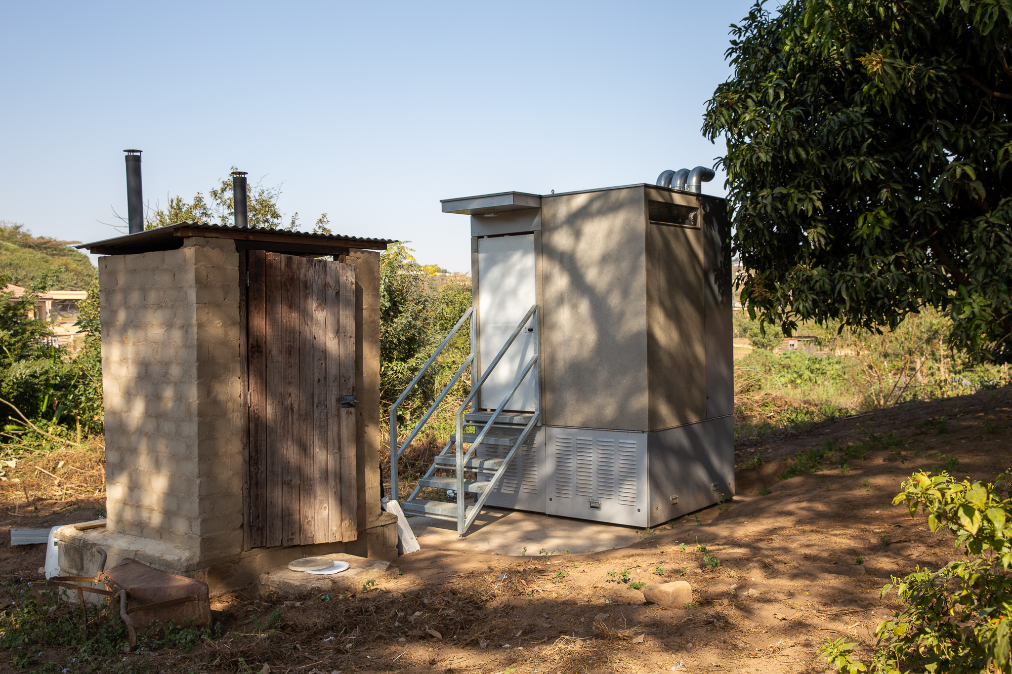 Test sul campo della toilette Blue Diversion Autarky accanto a una toilette a secco già esistente con separazione dell’urina (a sinistra) in un giardino di Durban, in Sudafrica. ©️ Autarky, Eawag