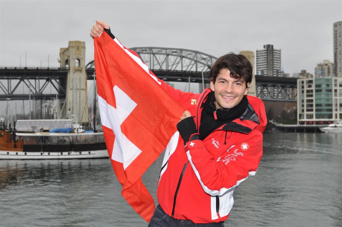 Der Schweizer Eiskunstläufer Stéphane Lambiel posiert während der Olympischen Winterspiele 2010 in Kanada auf der Terrasse des House of Switzerland in Vancouver stolz mit der Schweizer Flagge.
