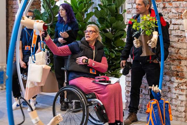 A visitor in a wheelchair interacts with an interactive design installation while exploring the House of Switzerland Milano exhibition.