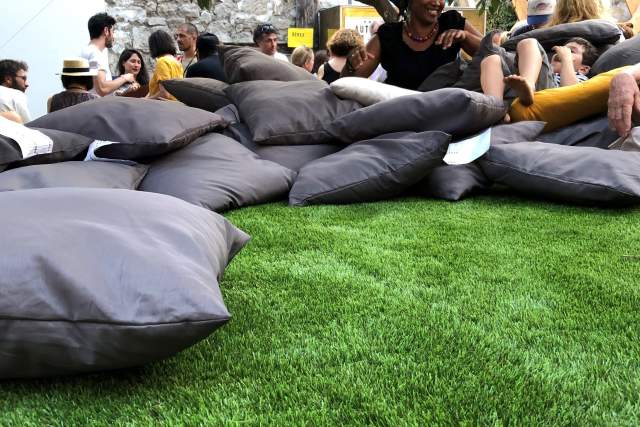 Green area with a bunch of sitting pillows and people chilling