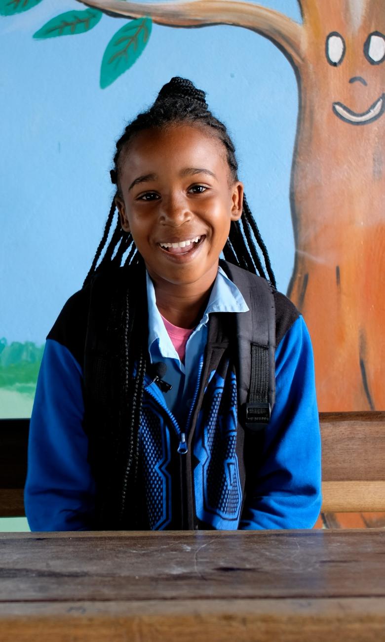 Lachendes Mädchen mit Schulrucksack im Kinderdorf Pestalozzi in Mosambik